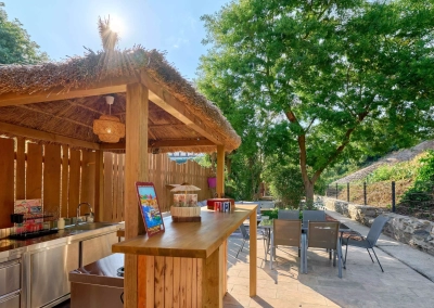 Bar extérieur sous paillote avec table et chaises.