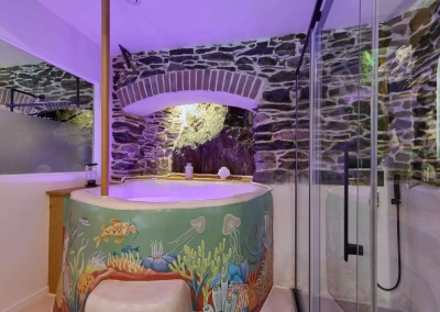 Baignoire balnéo ronde avec éclairage violet dans espace en pierre