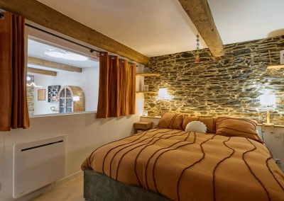 Mur en pierre éclairé derrière le lit dans la chambre Calypso