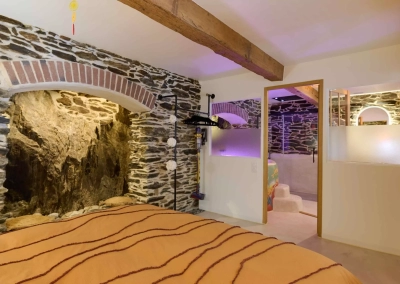 Chambre Calypso avec lit double et accès direct à la salle de bain spa avec murs en pierre