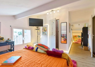 Vue d’ensemble de la Chambre Fauve à Collioure avec lit coloré, espace détente et salle de bain attenante.