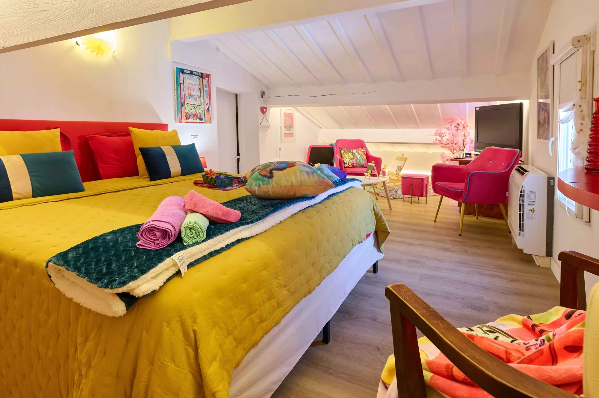 Vue d’ensemble de la Chambre Matisse à Collioure avec grand lit coloré et espace salon sous pente.