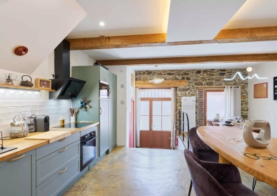 Vue depuis la cuisine vers la salle à manger du logement Le Calypso à Collioure, avec murs en pierre apparente.