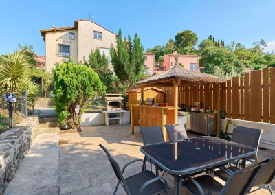 Paillote en bois avec bar et coin cuisine dans le jardin partagé.