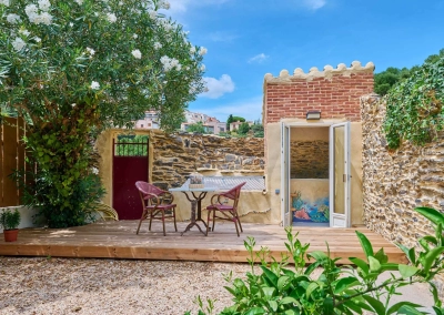 Terrasse en bois avec cabanon en pierre abritant le jacuzzi.